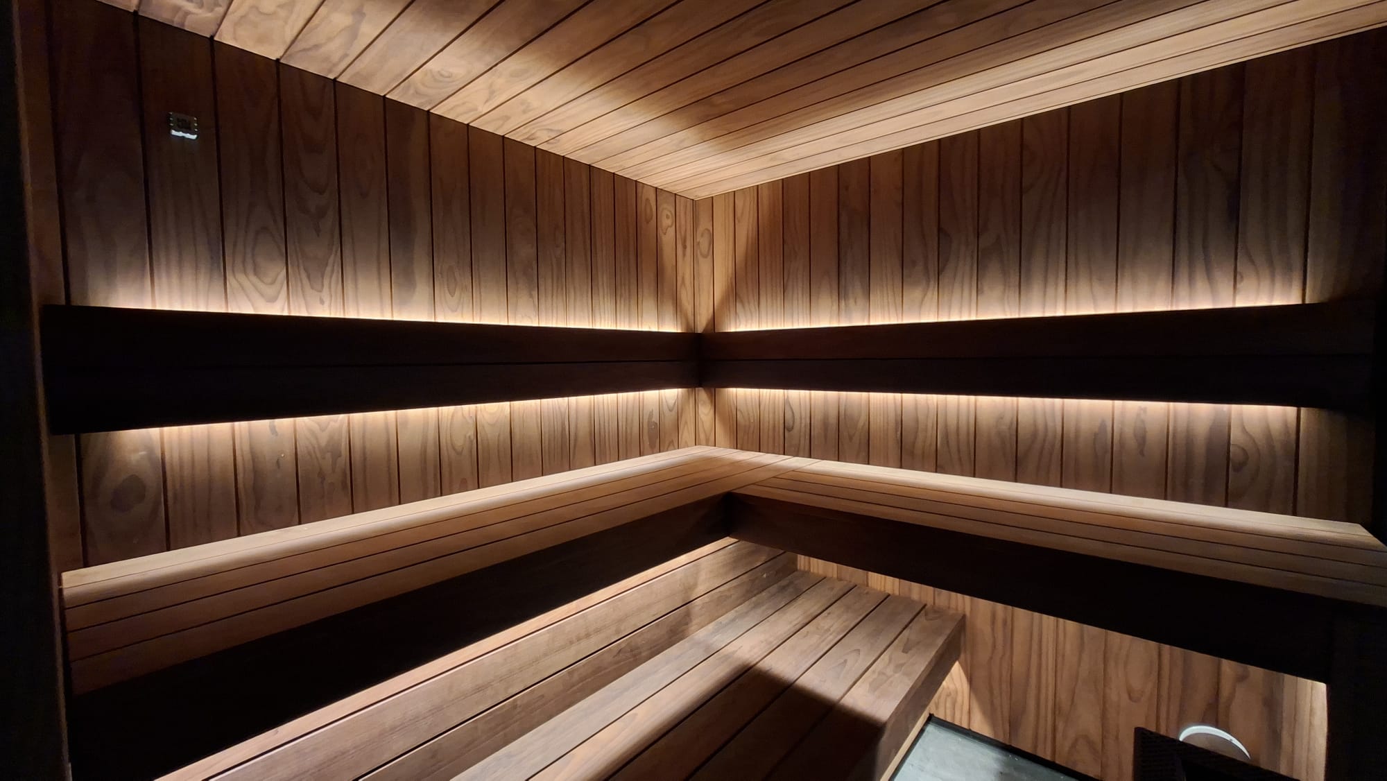 La sauna: bancos bajo una línea de luz cálida